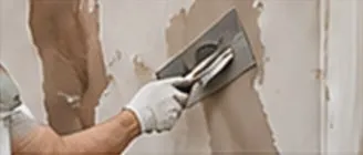 Skim coat being applied to a wall with a steel trowel